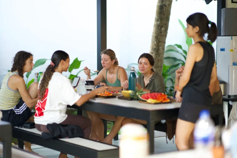 Students eating together at a dining table with plates of fruit and water bottles